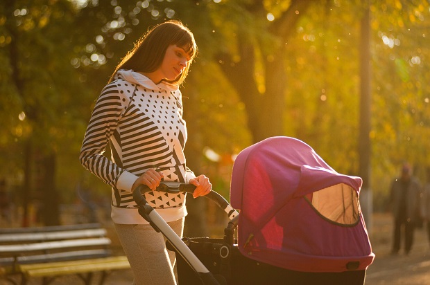 picture of a woman walking with stroller in the park on the sun