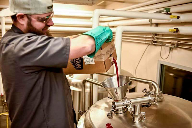 brewer-pouring-fruit-puree-from-oregron-fruit-products-into-craft-beer-tank